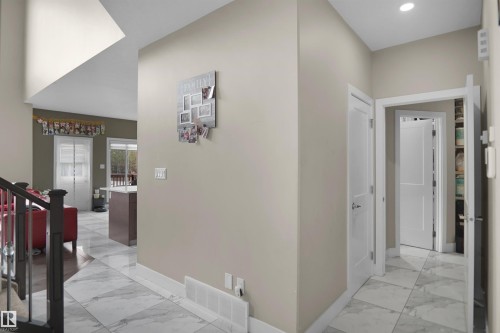 Foyer featuring large-format marble-look floor tiles, white trim, and a high ceiling - 6108 173 Ave, Edmonton, AB 