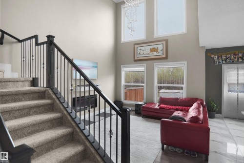 Two-story living area featuring a carpeted staircase with dark wood railings and decorative metal balusters - 6108 173 Ave, Edmonton, AB 