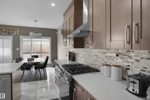 Modern kitchen featuring white countertops, stainless steel appliances, and wood-finish cabinetry - 6108 173 Ave, Edmonton, AB 