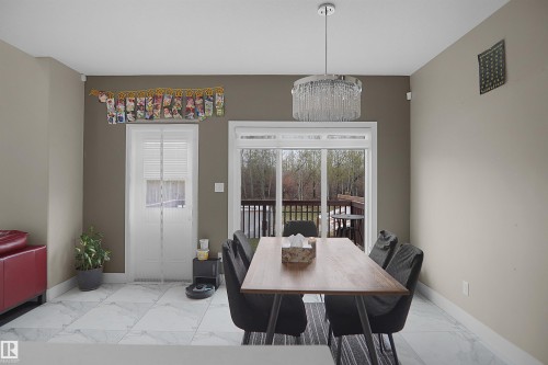 Spacious room featuring large format tile flooring, a glass slider door leading to an outdoor deck, a single window, and a contemporary chandelier - 6108 173 Ave, Edmonton, AB 