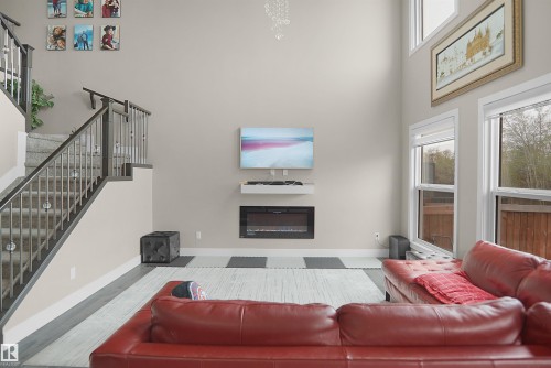 Two-story living area featuring a built-in electric fireplace with a floating mantle, high ceilings, and multiple large windows - 6108 173 Ave, Edmonton, AB 