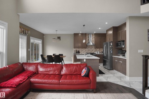 Open-concept living area featuring dark wood-finish flooring transitioning to light-toned tile - 6108 173 Ave, Edmonton, AB 