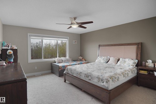 Carpeted bedroom featuring a large window, a ceiling fan with integrated lighting, and neutral wall tones - 6108 173 Ave, Edmonton, AB 