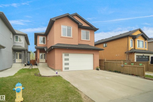 Contemporary two-story residence featuring a stucco exterior, attached garage with a modern panel door, and a concrete driveway - 6108 173 Ave, Edmonton, AB 