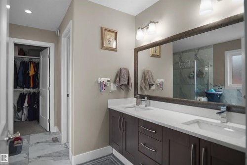 Bathroom featuring a double vanity with dark wood-finish cabinetry, white countertops, and dual undermount sinks - 6108 173 Ave, Edmonton, AB 