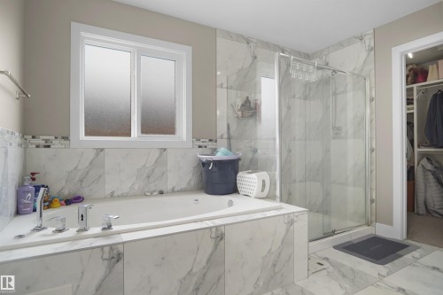 Spacious bathroom featuring a built-in jetted tub with polished chrome fixtures and an expansive shower enclosure with clear glass doors - 6108 173 Ave, Edmonton, AB 