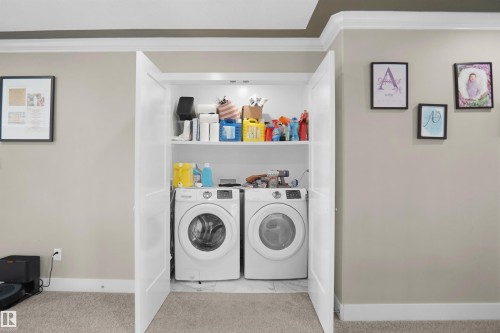 Dedicated laundry closet featuring a stacked shelf system, bi-fold doors, and a carpeted floor - 6108 173 Ave, Edmonton, AB 