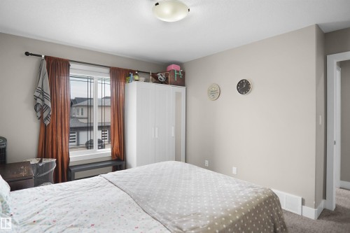 Bedroom featuring a flush-mount ceiling light, a window with white trim, and light-colored walls - 6108 173 Ave, Edmonton, AB 