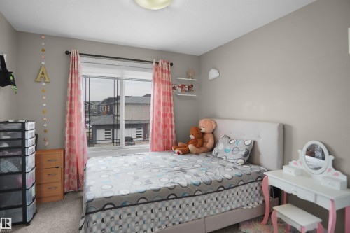 Bright bedroom with a window featuring horizontal and vertical muntins, light gray wall paint, and a ceiling-mounted light fixture - 6108 173 Ave, Edmonton, AB 