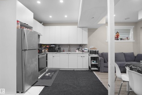 Contemporary kitchen featuring white cabinetry, stainless steel appliances, recessed lighting, and a tile backsplash - 6108 173 Ave, Edmonton, AB 