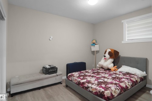 Room featuring light gray walls, wood-finish flooring, a window with horizontal blinds, and a flush-mount ceiling light - 6108 173 Ave, Edmonton, AB 