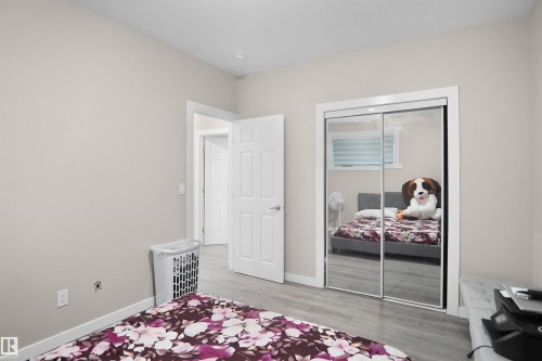 Bedroom featuring light gray walls, wood-finish flooring, a white trim package, and a mirrored sliding door closet - 6108 173 Ave, Edmonton, AB 