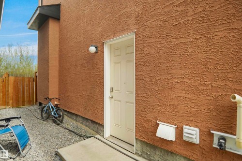 Textured stucco exterior with a side entry door, exterior wall light, and a sloped eave overhang - 6108 173 Ave, Edmonton, AB 
