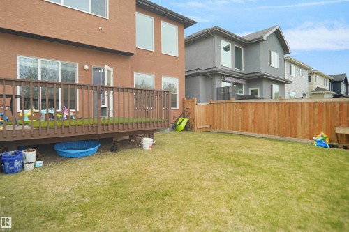 Spacious backyard featuring a wooden deck with railing, a grass lawn, and a tall privacy fence - 6108 173 Ave, Edmonton, AB 