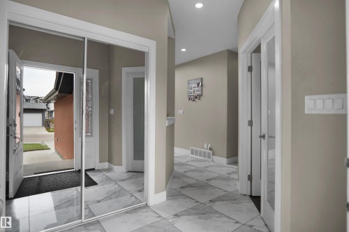 Entryway featuring large format marble-look tile flooring, a mirrored closet door, recessed lighting, and a glass-paneled interior door - 6108 173 Ave, Edmonton, AB 