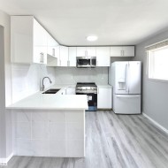 Kitchen featuring new white cabinetry, new countertops, new tile backsplash, new stainless over-the-range microwave, new electric stove, new dishwasher and LVP flooring. - 