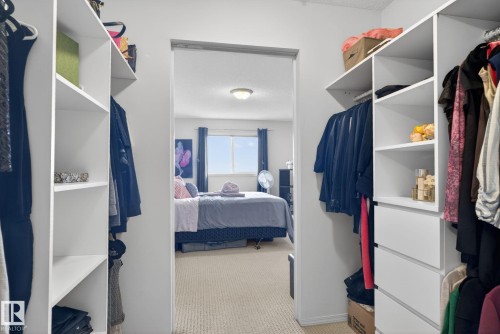 Walk-in closet featuring white shelving units with hanging space and drawers - 423 2430 Guardian Road, Edmonton, AB - Indoor With Storage