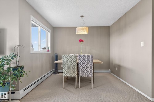 This dining space features carpeted flooring, a large window, and a modern light fixture - 423 2430 Guardian Road, Edmonton, AB - Indoor