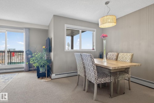 The dining area features a modern chandelier and a window providing natural light - 423 2430 Guardian Road, Edmonton, AB - Indoor Photo Showing Dining Room