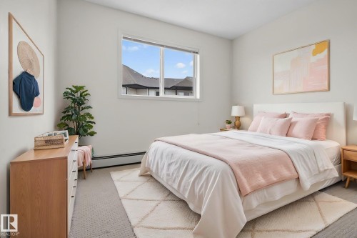 Bright room with light-colored walls and a window, featuring carpeted flooring and a baseboard heater - 423 2430 Guardian Road, Edmonton, AB - Indoor Photo Showing Bedroom