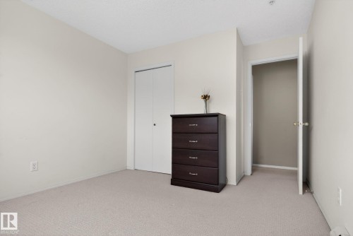 This room features light-colored walls and carpeting, a closet with bi-fold doors, and a doorway leading to another area - 423 2430 Guardian Road, Edmonton, AB - Indoor