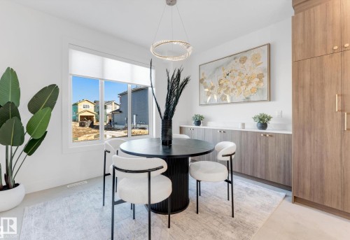 Dining area featuring a contemporary chandelier, large window, and light wood-finish built-in cabinetry with white countertops - 4727 17 Avenue, Edmonton, AB - Indoor Photo Showing Dining Room