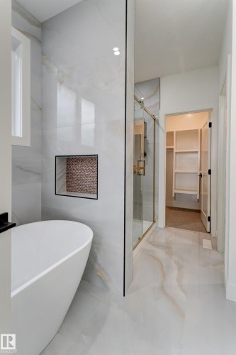 Freestanding soaking tub with a tiled accent wall featuring a recessed niche - 4727 17 Avenue, Edmonton, AB 
