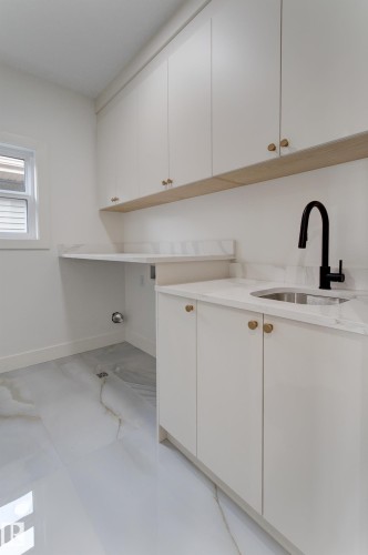 White cabinetry with gold-finish hardware and a light wood-finish accent shelf - 4727 17 Avenue, Edmonton, AB 