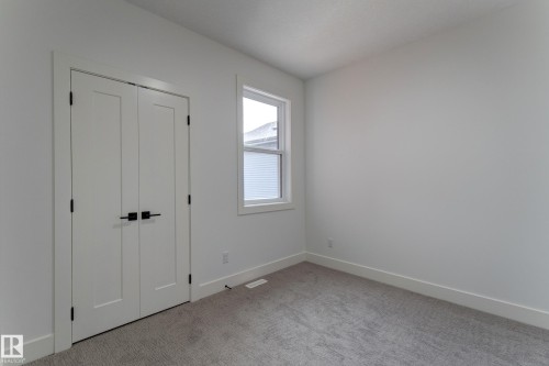 Interior room featuring neutral wall finishes, a single casement window, and a gray carpeted floor - 4727 17 Avenue, Edmonton, AB 