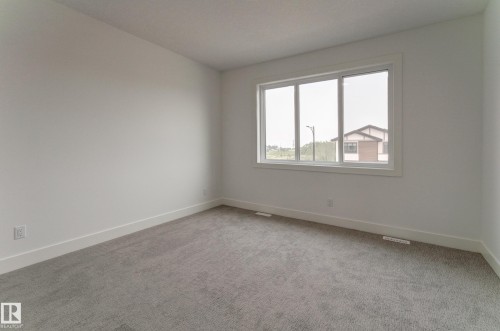 Spacious room featuring neutral carpeting and white baseboards - 4727 17 Avenue, Edmonton, AB 