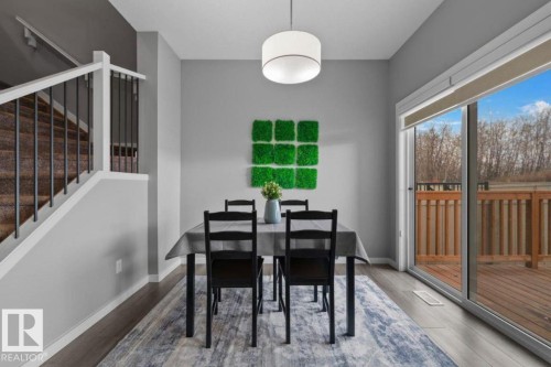 Dining area featuring wood-finish flooring, a contemporary drum pendant light, and a sliding glass door providing access to an exterior deck - 243 39 Avenue Nw, Edmonton, AB - Indoor Photo Showing Dining Room