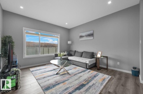 Spacious living area featuring a large window, neutral wall tones, wood-finish flooring, recessed lighting, and white baseboards - 243 39 Avenue Nw, Edmonton, AB - Indoor Photo Showing Living Room