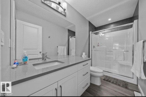 Bathroom featuring a dual-sink vanity with a light-toned countertop, white cabinetry, and brushed nickel hardware - 243 39 Avenue Nw, Edmonton, AB - Indoor Photo Showing Bathroom