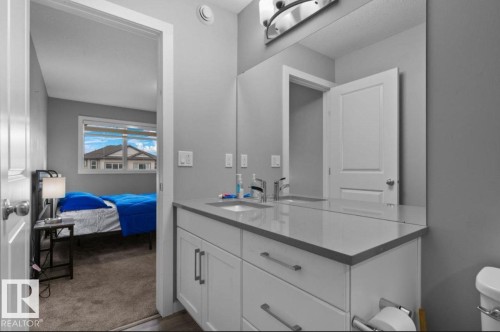 Bathroom vanity featuring dual sinks, white cabinetry with silver hardware, and a light-colored countertop - 243 39 Avenue Nw, Edmonton, AB - Indoor Photo Showing Bathroom