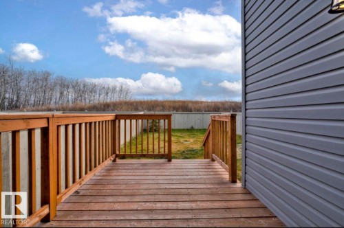 Wooden deck with natural finish, featuring a wood railing with vertical spindles - 243 39 Avenue Nw, Edmonton, AB - Outdoor With Exterior