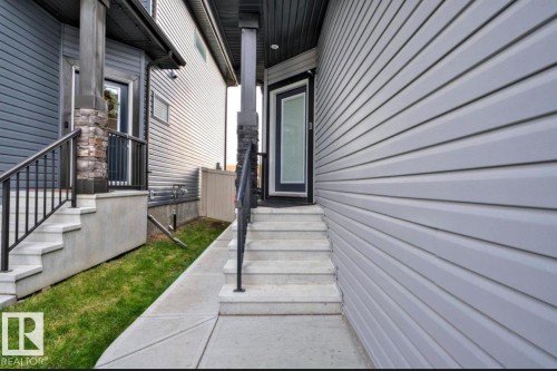 Light gray horizontal siding with a black framed door and concrete steps featuring a black metal handrail - 243 39 Avenue Nw, Edmonton, AB - Outdoor With Exterior