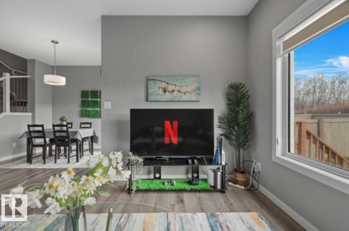 Open-concept living area featuring wood-finish flooring, neutral paint, and a large window - 243 39 Avenue Nw, Edmonton, AB - Indoor