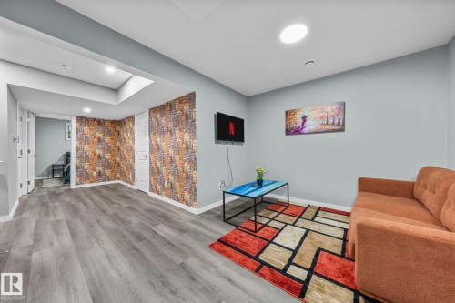 Spacious living area featuring wood-finish flooring and recessed lighting - 243 39 Avenue Nw, Edmonton, AB - Indoor