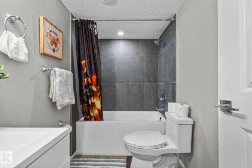 Bathroom featuring a white tub, shower with dark grey tile surround, recessed lighting, and a white vanity with a rectangular sink - 243 39 Avenue Nw, Edmonton, AB - Indoor Photo Showing Bathroom