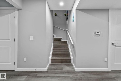 Interior staircase featuring wood-finish treads and risers, a white handrail, and light gray wall paint - 243 39 Avenue Nw, Edmonton, AB - Indoor Photo Showing Other Room