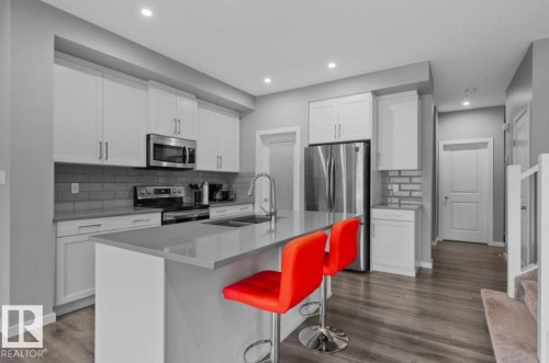 Well-appointed kitchen featuring white cabinetry, stainless steel appliances, a subway tile backsplash, and a central island with an undermount sink - 243 39 Avenue Nw, Edmonton, AB - Indoor Photo Showing Kitchen With Stainless Steel Kitchen With Upgraded Kitchen