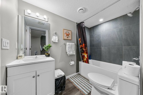 Bathroom featuring a white vanity with integrated sink, rectangular mirror, and three-bulb vanity lighting - 243 39 Avenue Nw, Edmonton, AB - Indoor Photo Showing Bathroom