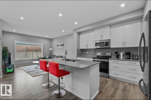 Modern kitchen featuring white shaker cabinetry, stainless steel appliances, and a grey subway tile backsplash - 243 39 Avenue Nw, Edmonton, AB - Indoor Photo Showing Kitchen With Stainless Steel Kitchen With Upgraded Kitchen