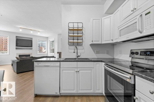 Contemporary kitchen featuring white cabinetry and dark countertops - 304 10011 110 Street, Edmonton, AB - Indoor Photo Showing Kitchen