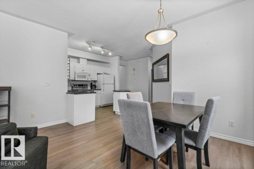 Open-concept living space featuring wood-finish flooring, white walls, and a modern kitchen - 304 10011 110 Street, Edmonton, AB - Indoor Photo Showing Dining Room