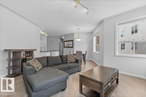 Open-concept living area featuring wood-finish flooring, white trim, and track lighting - 304 10011 110 Street, Edmonton, AB - Indoor Photo Showing Living Room