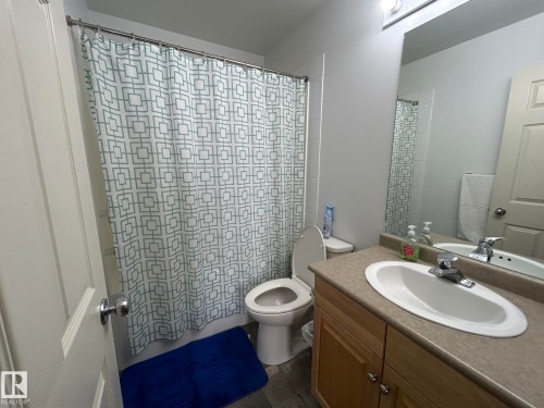 Full bathroom featuring a single vanity with wood-finish cabinetry, a large mirror, and a shower-tub combination with white subway tile surround - 304 10011 110 Street, Edmonton, AB - Indoor Photo Showing Bathroom