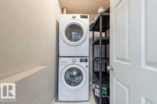 Dedicated laundry area featuring stacked front-load washer and dryer units - 304 10011 110 Street, Edmonton, AB - Indoor Photo Showing Laundry Room