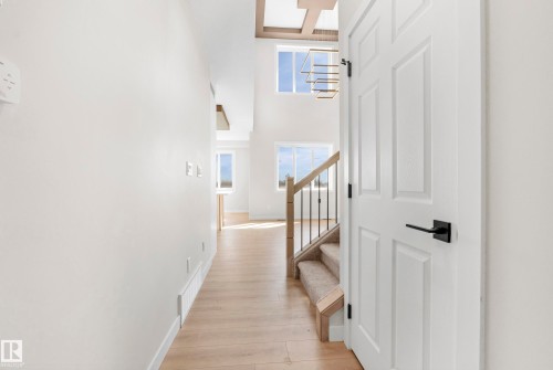 Entryway featuring light wood-finish flooring and a white paneled door with modern black hardware - 4915 17 Avenue, Edmonton, AB - Indoor Photo Showing Other Room