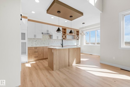 Modern kitchen featuring two-tone cabinetry, a central island with a sink, and integrated overhead lighting - 4915 17 Avenue, Edmonton, AB - Indoor Photo Showing Kitchen